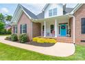 Close-up of the front exterior featuring a brick facade, a bright blue door and rocking chairs on the front porch at 3178 Newcastle Dr # 42, Rock Hill, SC 29732