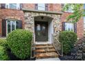 Close-up of the stone front porch, steps, and iron door of a beautiful red brick home at 3206 Lakehurst Xing, Matthews, NC 28104
