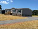 Charming gray home featuring a gravel driveway, wooden steps, and brick foundation at 493 Eagle Mills Rd, Hamptonville, NC 27020