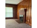 This home features a living room with wood paneling, a brick fireplace, and a window with blinds at 610 E Maryland Ave, Bessemer City, NC 28016