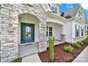 Close-up of a stone arched entrance with teal front door, mulch landscaping, and exterior columns at 7160 Sumters Camp Trl, Indian Land, SC 29707