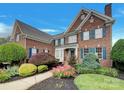 Charming brick home featuring lush landscaping, vibrant flowers, and a welcoming front entrance at 1000 Sarandon Dr, Matthews, NC 28104