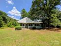 Quaint single-story home with light blue siding, white trim, surrounded by a lush green lawn and mature trees at 647 Mckay Hill Rd, Mount Gilead, NC 27306