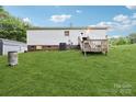 View of the rear of the house with a small wooden deck and large grassy yard at 103 Palace Pt, Kings Mountain, NC 28086