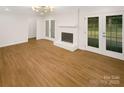 Bright living room features a painted brick fireplace, wood floors, and glass doors to the outside at 1212 Beechdale Dr, Charlotte, NC 28212