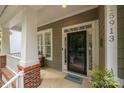 Inviting covered front porch with brick accents and charming entry door at 15913 Trenton Place Rd, Huntersville, NC 28078