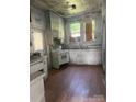 Shows a kitchen in need of renovation with outdated appliances and cabinetry on wood floors at 169 Saluda St, Chester, SC 29706