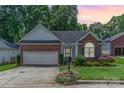 Charming single-story brick home with a well-maintained lawn and attached two-car garage at dusk at 2333 Wednesbury Ct, Kannapolis, NC 28083
