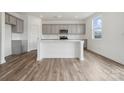 Modern kitchen featuring an island, gray cabinets, white backsplash, wood-look flooring and stainless steel microwave at 2592 Blue Sky Meadows Dr, Monroe, NC 28110