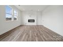 Bright living room with fireplace, large windows, wood-look flooring, and modern finishes at 2592 Blue Sky Meadows Dr, Monroe, NC 28110