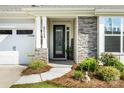 Inviting front entrance with stone accents, lush landscaping, and a decorative glass door at 2658 Manor Stone Way, Indian Trail, NC 28079