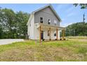 Inviting two-story home with a covered front porch, gray accents, well-maintained landscaping, and a driveway on the side at 27 Mickley Ave, Bessemer City, NC 28016