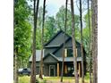 Two-story modern farmhouse with dark siding, a garage, and natural wood accents nestled in a wooded lot at 3020 Quiet Ln, Iron Station, NC 28080