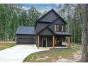 Modern farmhouse with dark siding, garage, natural wood porch columns, and a concrete driveway at 3020 Quiet Ln, Iron Station, NC 28080