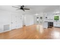 Open living room featuring hardwood floors, white walls, a ceiling fan and access to the updated kitchen at 3103 Suggs St, Belmont, NC 28012