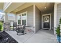 Inviting front porch featuring rocking chairs, stone pillar accents, and a decorated glass front door at 3833 Isenhour Rd, Kannapolis, NC 28081