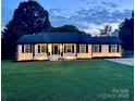 Charming ranch-style home with a well-manicured lawn at twilight at 554 Isle Of Pines Rd, Mooresville, NC 28117