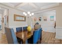 Dining room with coffered ceiling, wood table, elegant chandelier, and wainscoting at 107 Hornbeam Ln, Mooresville, NC 28117