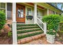 Close-up of a brick front porch with wooden door and decorative plants enhancing curb appeal at 2025 Sagamore Rd, Charlotte, NC 28209