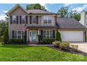 Two-story home featuring black shutters, an American flag, a well-manicured lawn, and a two-car garage at 204 Pebble Creek Xing, Fort Mill, SC 29715
