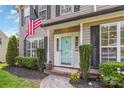 A close up view of the front door featuring a light blue door, an American flag, and manicured landscaping at 204 Pebble Creek Xing, Fort Mill, SC 29715