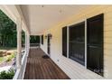 View of the covered front porch, featuring dark shutters, wooden flooring, and ample space for outdoor seating at 219 Proctor Dr, Salisbury, NC 28147