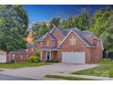 Brick home with a large driveway, well-kept lawn, and basketball hoop on a sunny day at 3741 Tea Olive Rd, Gastonia, NC 28056