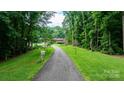 Scenic driveway leading to a charming brick home framed by lush greenery and mature trees at 4916 Leepers Creek Rd, Maiden, NC 28650