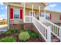 Close-up of front porch featuring white railing, brick foundation, and landscaped flower bed at 509 Brawley Rd # 7, Cleveland, NC 27013