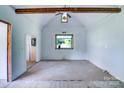 Bright living room featuring exposed wood beam, a large window, and an open floor plan at 5604 Nc 152 E Hwy, Rockwell, NC 28138