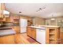 Traditional kitchen featuring wood cabinets, laminate countertops, white appliances, and hardwood floors at 6227 Dogwood Ln, Waxhaw, NC 28173