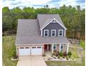 Aerial view of a charming two-story home with a well-manicured lawn, two-car garage, and a cozy front porch at 10100 Jack Nicklaus Dr, Lancaster, SC 29720