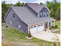 View of home with stone accents, gray siding, a two-car garage, concrete driveway and well-maintained lawn at 10100 Jack Nicklaus Dr, Lancaster, SC 29720