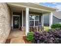 Inviting front porch with rocking chairs, brick accents, and lush landscaping create a warm welcome at 17028 River Race Dr, Huntersville, NC 28078