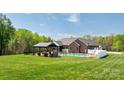 This backyard features a pool, covered patio with fireplace, and fenced in yard at 2458 Genelia Dr, Claremont, NC 28610