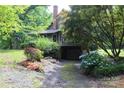 View of backyard with mature trees and landscaping, including hydrangeas, leading to a basement garage at 344 Lucas Rd, Star, NC 27356