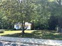 Quaint single-Gathering home featuring a brick chimney, blue shutters, and mature trees at 555 Ridge Ave, Mooresville, NC 28115