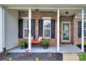 Inviting front porch with brick detail, white columns, and cozy bench seating with colorful pillows at 5748 Timbertop Ln, Charlotte, NC 28215