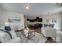 Open-concept living room showcasing hardwood floors, comfortable seating, and a modern kitchen in the background at 5836 Clan Maclaine Dr, Charlotte, NC 28278