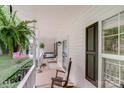 Relaxing covered porch with a swing, rocking chair and hanging fern at 592 Woodcrest Dr, Gastonia, NC 28056