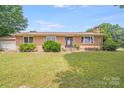Charming brick home featuring a well-maintained lawn, complemented by mature greenery, and a welcoming front entrance at 6300 Mount Pleasant S Rd, Concord, NC 28025