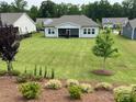Expansive backyard featuring lush lawn, mature trees, and beautiful landscaping at 7057 Kingfisher Way, Belmont, NC 28012