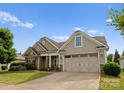A well-maintained home with a two-car garage, stone accents, neutral siding, and landscaping at 8830 Artesa Mill Ln, Charlotte, NC 28214