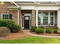 Close-up of home entrance with a dark door and stone surround, framed by lush landscaping and manicured lawn at 8830 Artesa Mill Ln, Charlotte, NC 28214