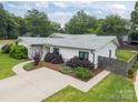 Well-manicured lawn and landscaping surround the home showcasing its gray shingle roof and white siding at 1207 Lakedell Dr, Charlotte, NC 28215
