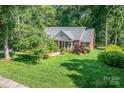 A picturesque exterior featuring a classic brick home with lush green surroundings and mature trees at 122 Waterford Dr, Mooresville, NC 28117