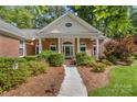 Inviting entrance to brick home with manicured landscaping leading to a charming front porch with rocking chairs at 122 Waterford Dr, Mooresville, NC 28117