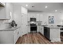 Modern white kitchen with stainless steel appliances, granite countertops, and wood flooring at 3128 Butler Hill Dr, Matthews, NC 28105