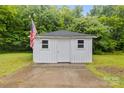 Storage building with a gray roof, white siding, and an American flag displayed in the back yard at 653 Turner St, Mooresville, NC 28115