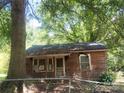 Exterior view of a small weathered home with a chainlink fence, surrounded by overgrown trees at 711 East Dr, Cherryville, NC 28021
